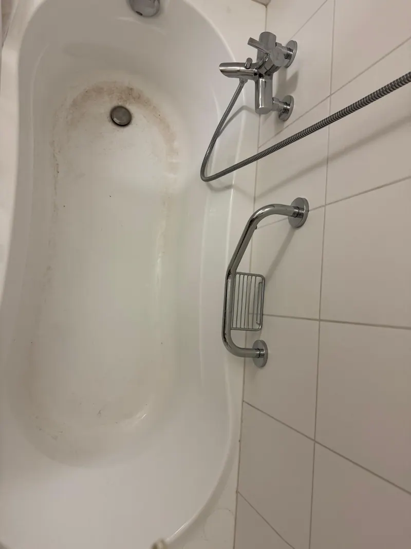 Même baignoire avant l’intervention, avec des salissures visibles.